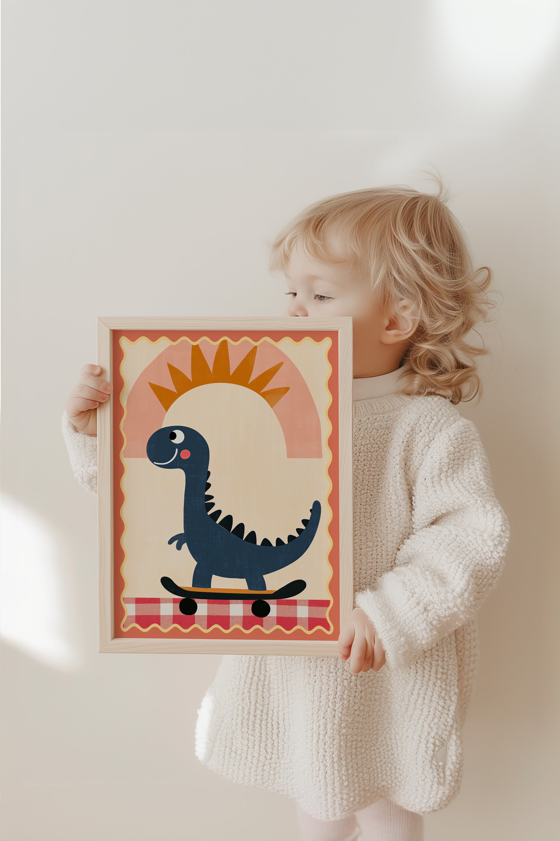 Fröhliches Kind hält das Poster "Dino auf Skateboard mit Sonne" von justgoodmood, ein lustiger Dinosaurier in Boho Farben, perfekt für das Kinderzimmer.