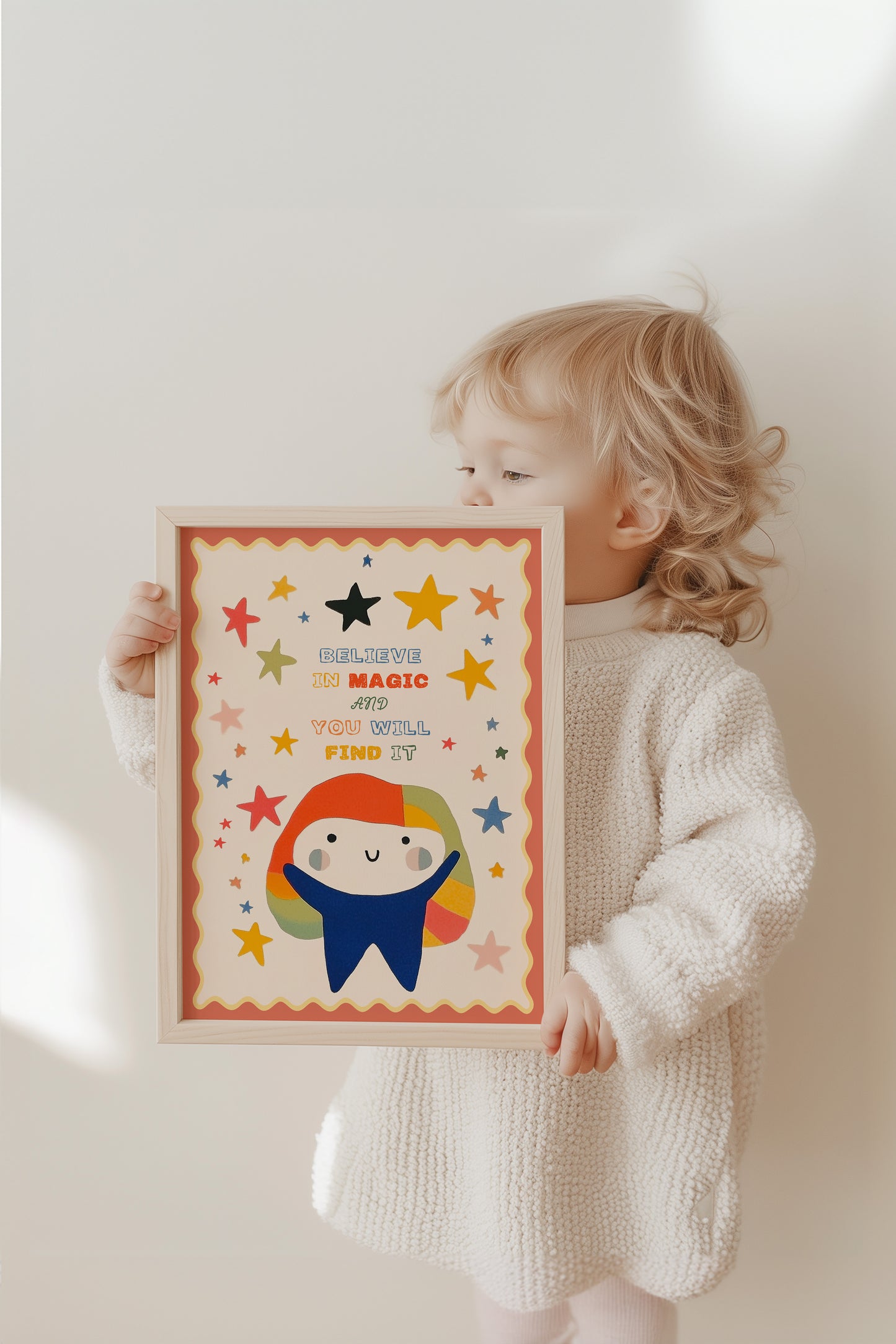 Kleines Kind hält mit Freude das farbenfrohe Poster "Believe in Magic" von justgoodmood, ideal für das Kinderzimmer von Träumern.