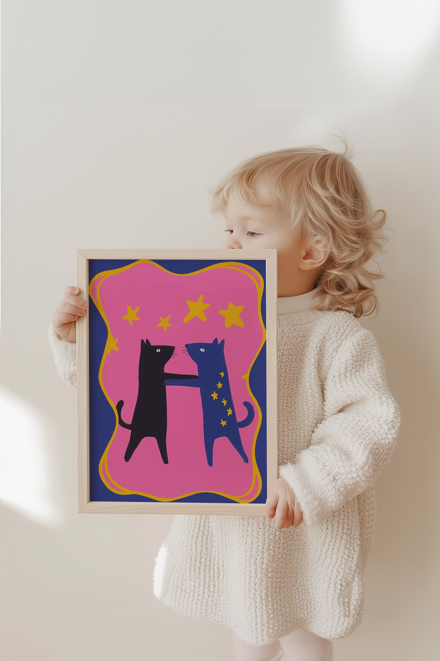 Ein fröhliches Kind hält das bunte Katzen-Poster von justgoodmood, das Freundschaft und Magie im Kinderzimmer ausstrahlt.