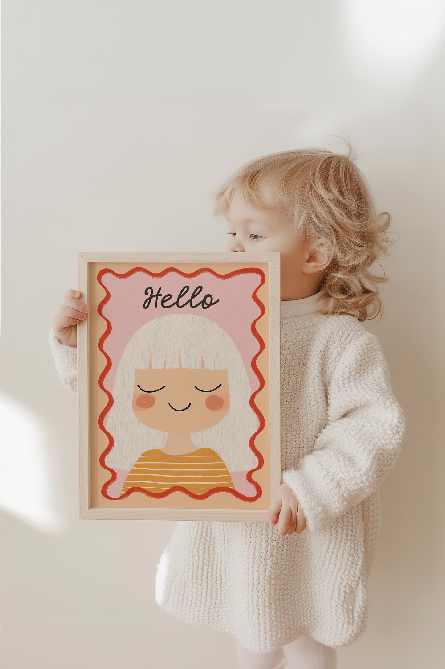 Ein Kind hält das fröhliche Poster von JUSTGOODMOOD, das ein Mädchen mit weißen Haaren und dem Schriftzug 'Hello' darstellt. Das positive Design macht es zur idealen Wanddekoration für das Kinderzimmer.