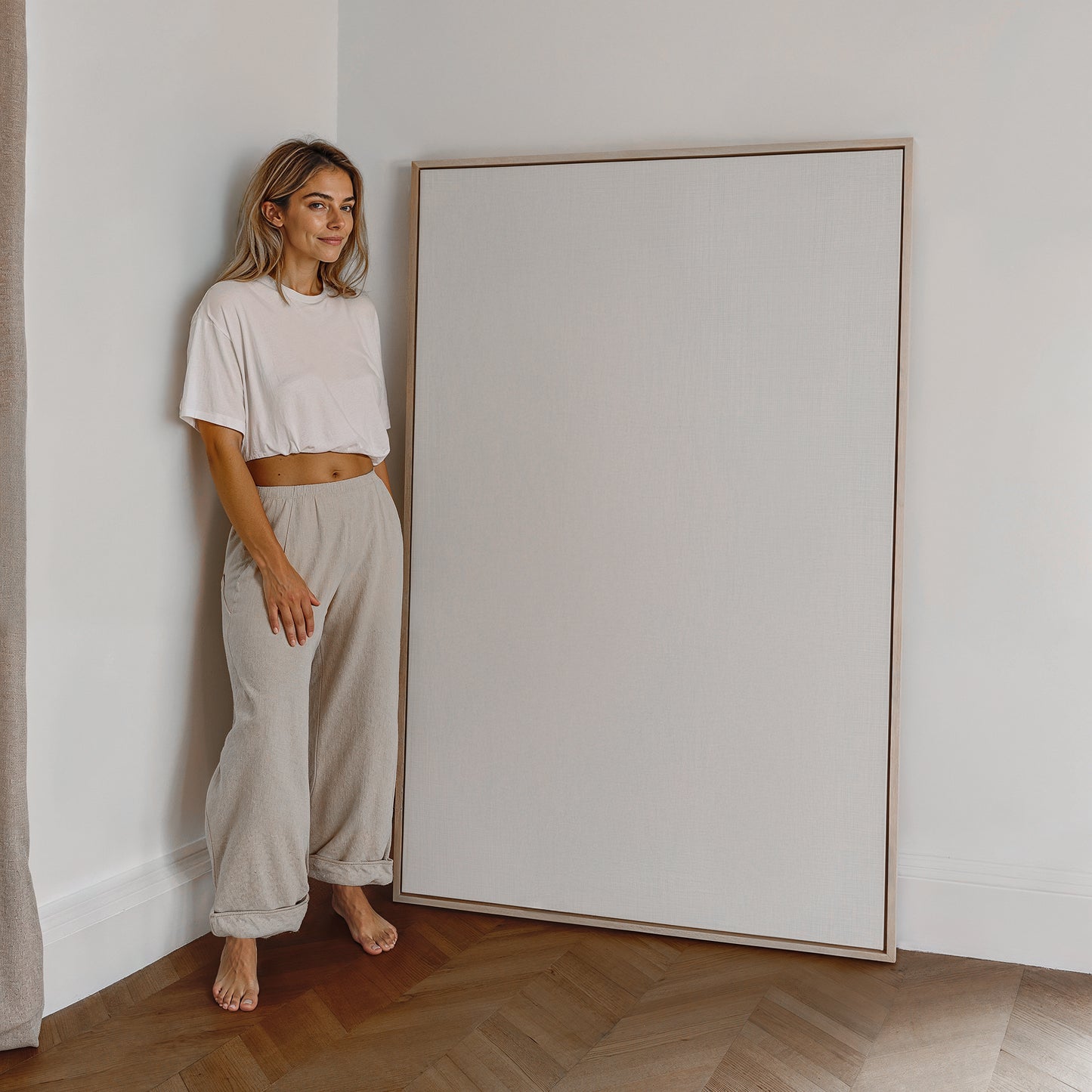 Eine Frau steht neben einem großen, leeren Rahmen, bereit, ein personalisierbares Foto als Poster von JUSTGOODMOOD einzufügen.