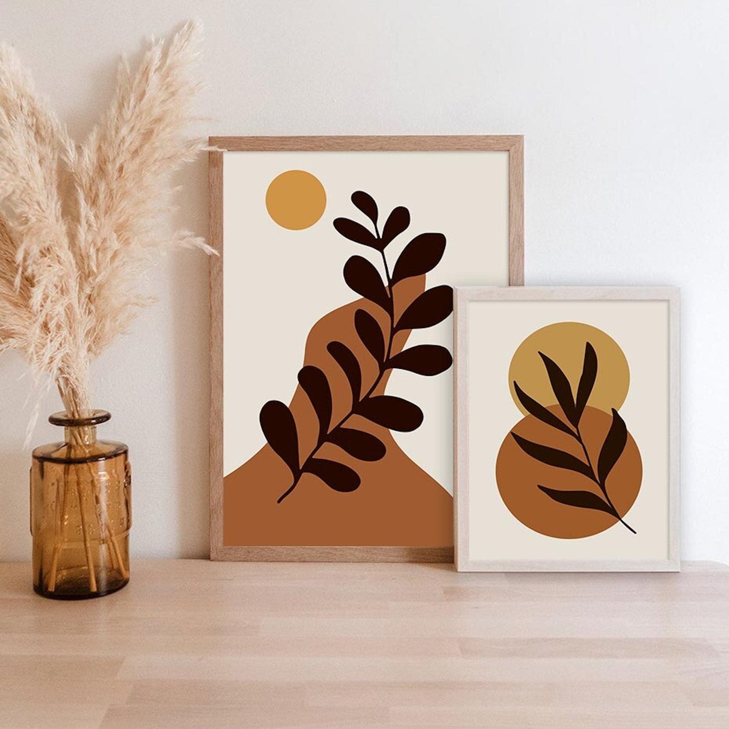 Zwei charmante Boho-Poster in sanften Ockar- und Beigetönen von justgoodmood, zusammen mit einer dekorativen Vase in einem stilvollen Zuhause.