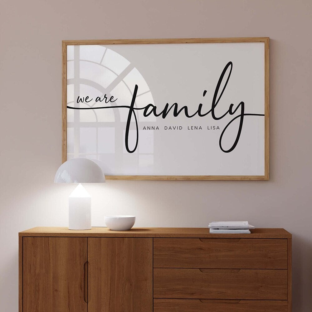 Personalisierte Familie Poster von justgoodmood, das die Worte 'we are family' mit den Namen Anna, David, Lena und Lisa in einem modernen Rahmen zeigt. Ideal als kreative Wanddekoration für ein Zuhause.