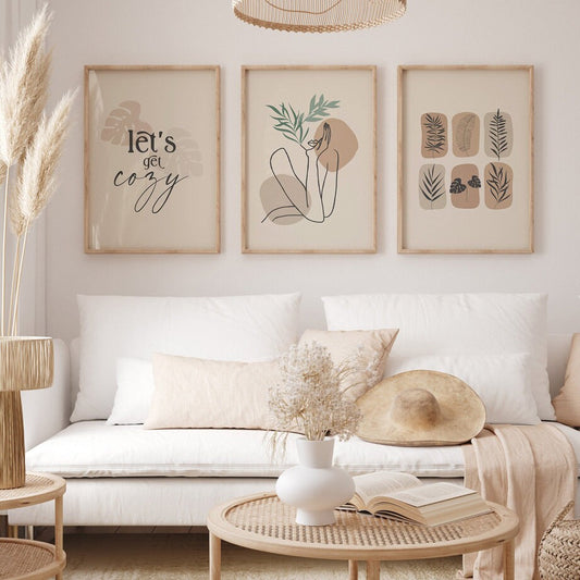 Wunderschöne Wanddekoration 'Let's Go Cozy' von justgoodmood, stilvoll angeordnet im hellen Wohnzimmer auf einem weißen Sofa mit Trockenblumen und einem Hut.