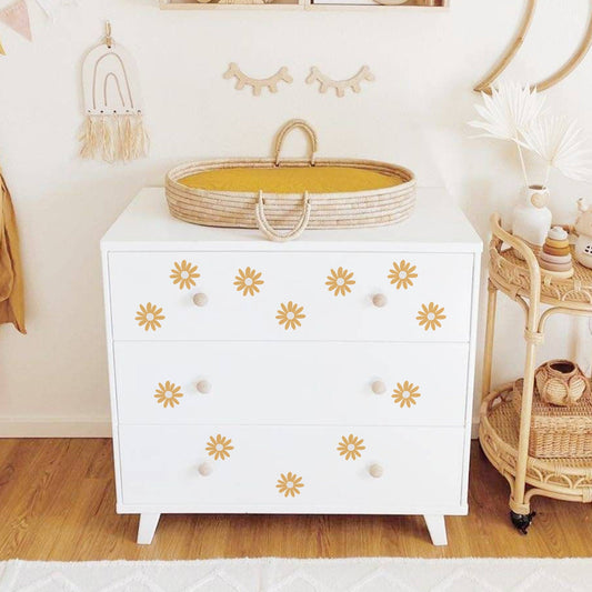 Elegante Kommode im Kinderzimmer dekoriert mit Boho Blumen Wandaufklebern von justgoodmood. Die Kommode ist mit liebevollen Blumenstickern verziert, die eine einladende Atmosphäre im Raum schaffen.