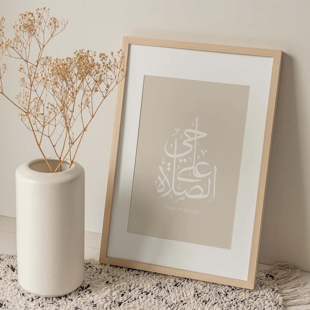 Inspirierendes Poster mit islamischer Kalligraphie von justgoodmood, dekorativ in einem Holzrahmen, umgeben von einer Vase und einem Teppich.
