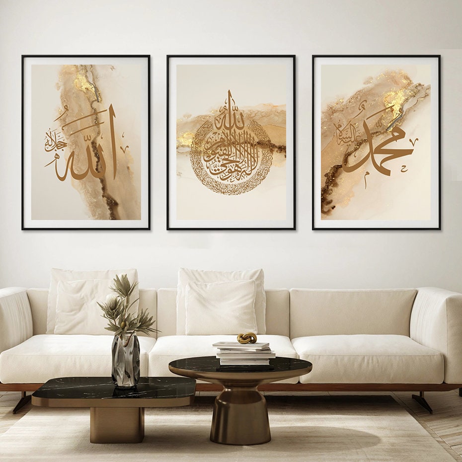 Drei beeindruckende Poster Arabische Kalligraphie in Gold von justgoodmood, stilvoll arrangiert über einem modernen Sofa in einem eleganten Wohnraum.