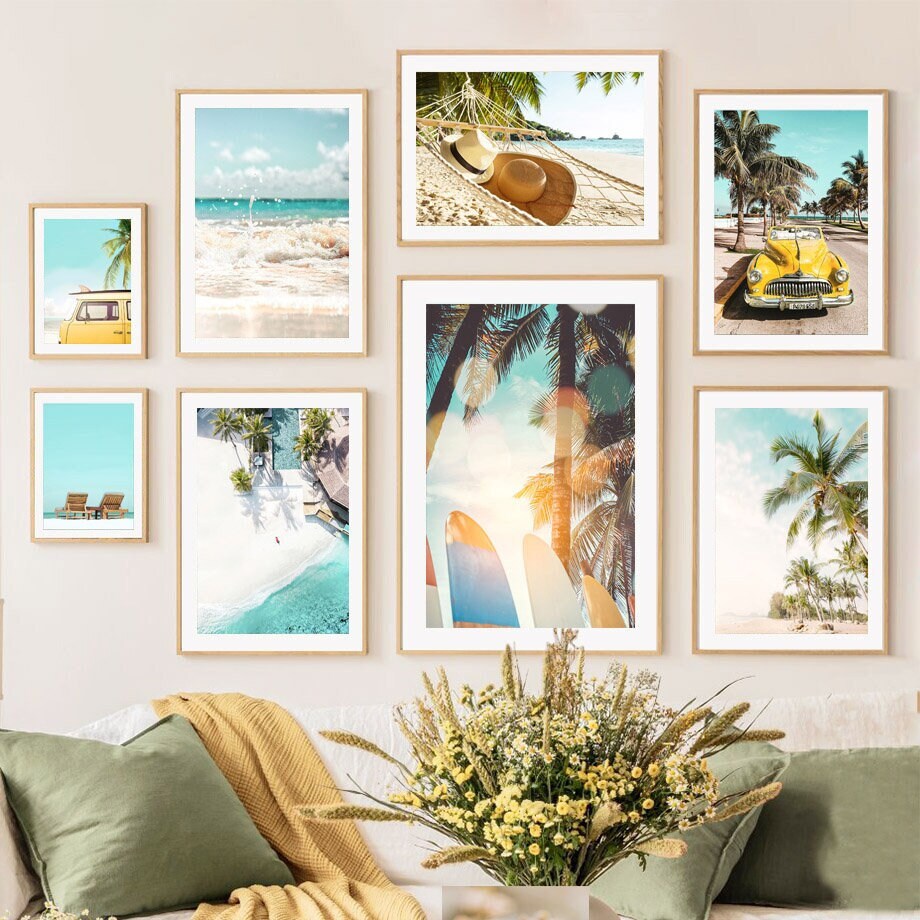 Fröhliche Wandgestaltung mit gerahmten Kunstwerken im tropischen Stil, einschließlich des Posters 'Sonnenschein Hängematte Palmen Meer' von justgoodmood. Perfekt für Wohnzimmer und Schlafzimmer, strahlt dieses Design Ruhe und Urlaubsstimmung aus.