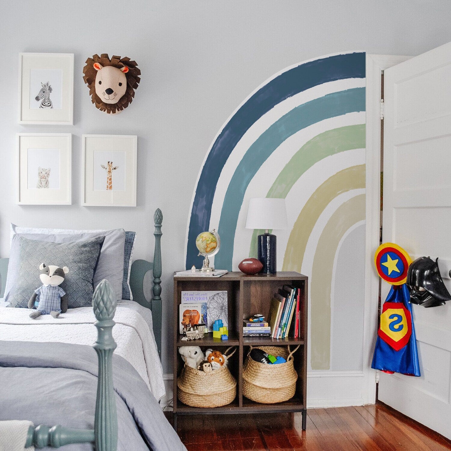 Charmantes Kinderzimmer mit Wandaufkleber eines Regenbogens und dekorativen Elementen wie einem Globus und Kuscheltieren. Stilvolle Wanddeko von justgoodmood, um eine fröhliche Atmosphäre zu schaffen.
