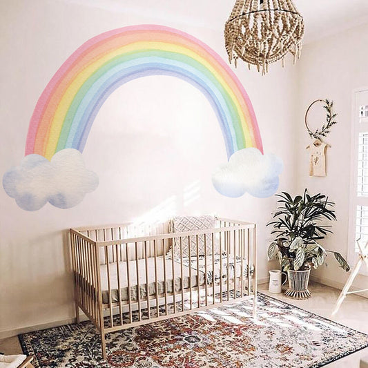 Bunte Regenbogen-Wandaufkleber von justgoodmood, die die Wand eines Babyzimmers schmücken, zusammen mit Wolken und einem gemütlichen Kinderbett.