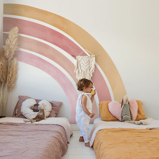 Farbenfrohes Kinderzimmer mit Regenbogen-Wandaufklebern von justgoodmood. Das Bild zeigt ein spielendes Kind in einem hellen Raum mit Wolkenmotiven und warmen Farbtönen, ideal für die Wand Deko im Babyzimmer.