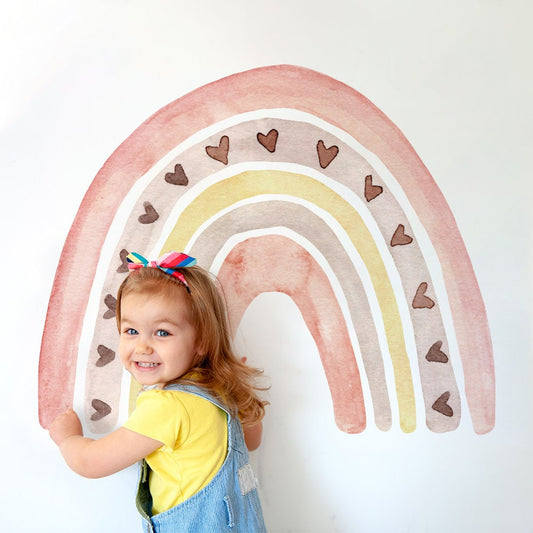 Fröhliches Mädchen mit einem bunten Regenbogen-Wandtattoo im Boho Stil von justgoodmood, ideal für Kinderzimmer Deko.