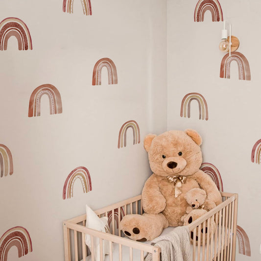 Gemütlich dekoriertes Kinderzimmer mit Boho Regenbogen Wandtattoos von justgoodmood, darunter ein großes Plüschtier, das eine liebevolle Atmosphäre ausstrahlt.