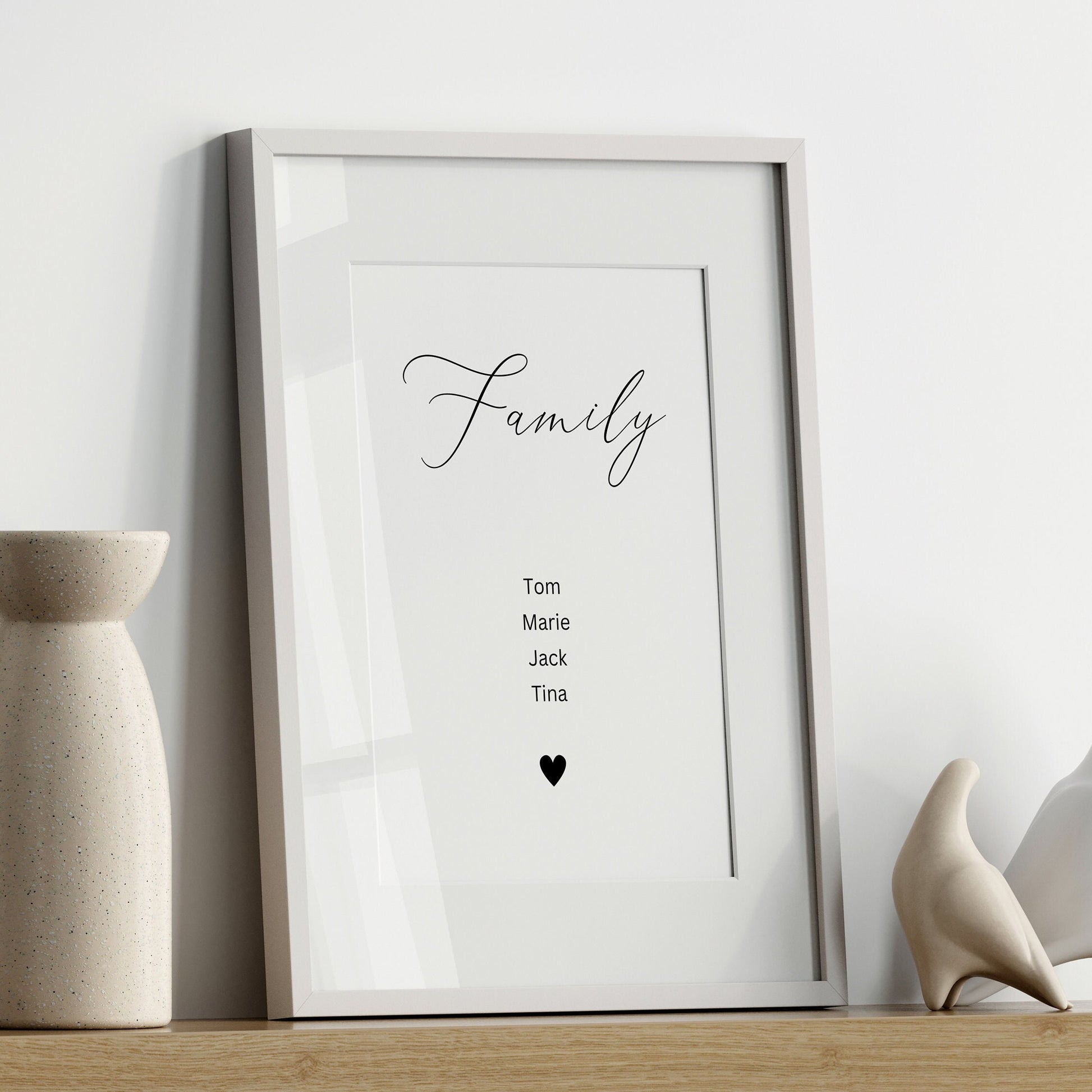 Personalisierte Familienposter von justgoodmood mit dem Titel 'Familie'. Es zeigt ein elegantes Wandbild mit den Namen Tom, Marie, Jack und Tina, umgeben von einem stilvollen Rahmen. Perfekte Wanddekoration für Wohnzimmer oder Schlafzimmer.
