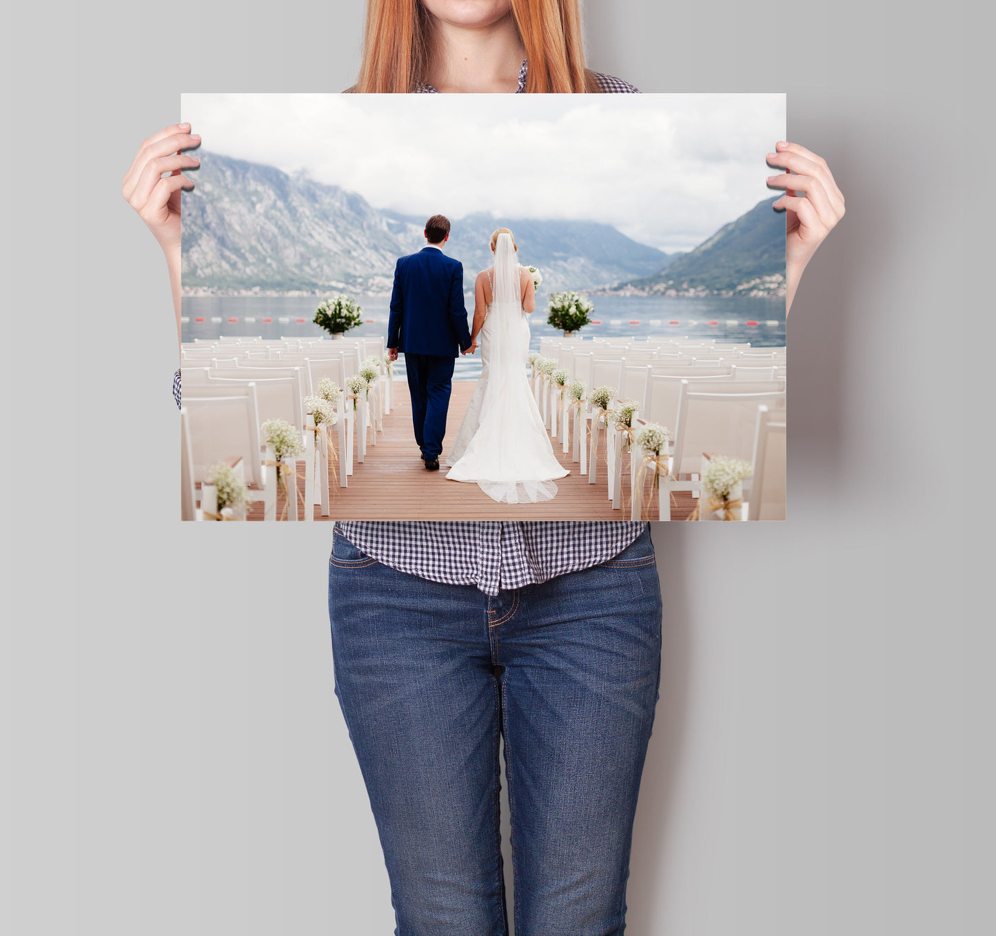 Ein Brautpaar geht Hand in Hand und zeigt ein großes Poster von justgoodmood, das den besonderen Moment ihrer Hochzeit festhält.
