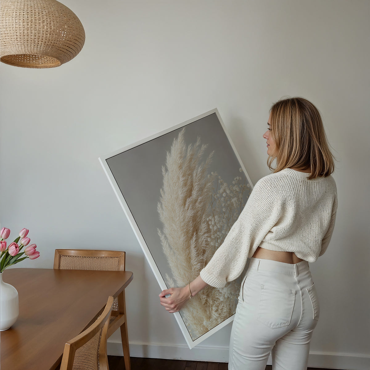 Motiv mit cremeweißen Pampaswedeln neben zartem weißen Schleierkraut vor grauem Hintergrund, über einem Bett im hellen Schlafzimmer.