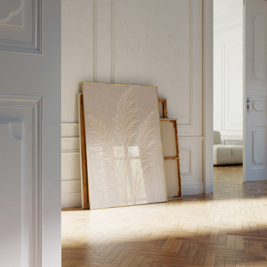 Motiv mit drei cremeweißen Pampaswedeln in Reliefoptik auf beigefarbenem Hintergrund, als an die Wand gelehntes Poster neben leeren Rahmen.