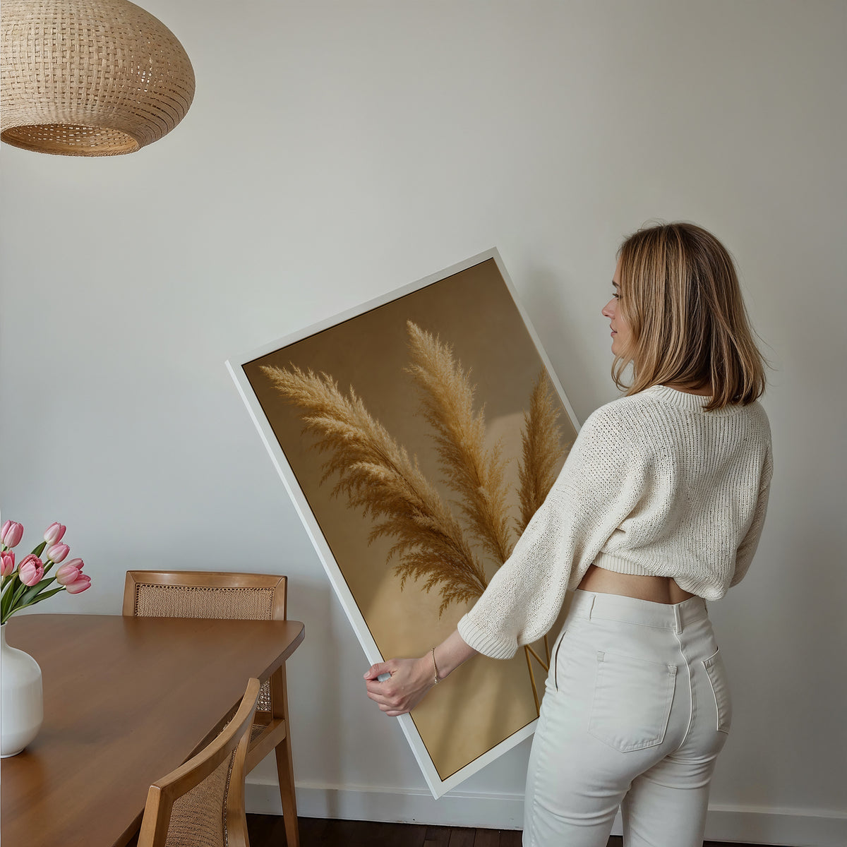 Motiv mit drei goldenen Pampaswedeln mit langen Schatten auf warmbeigem Hintergrund, über einem Bett im hellen Schlafzimmer.