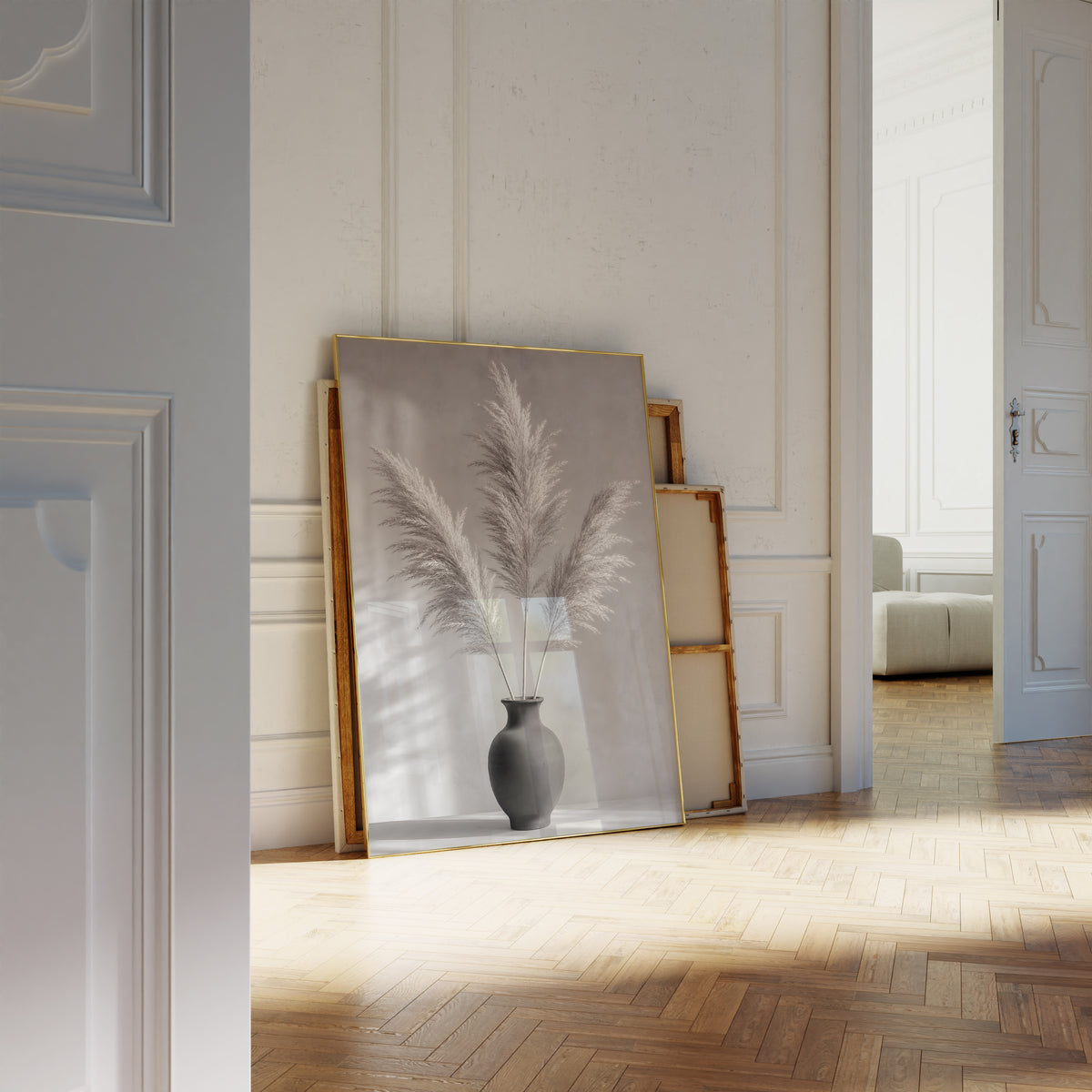 Motiv mit drei Pampaswedeln in einer schwarzen Vase vor einer grauen Wand mit Schatten, als an die Wand gelehntes Poster neben leeren Rahmen.