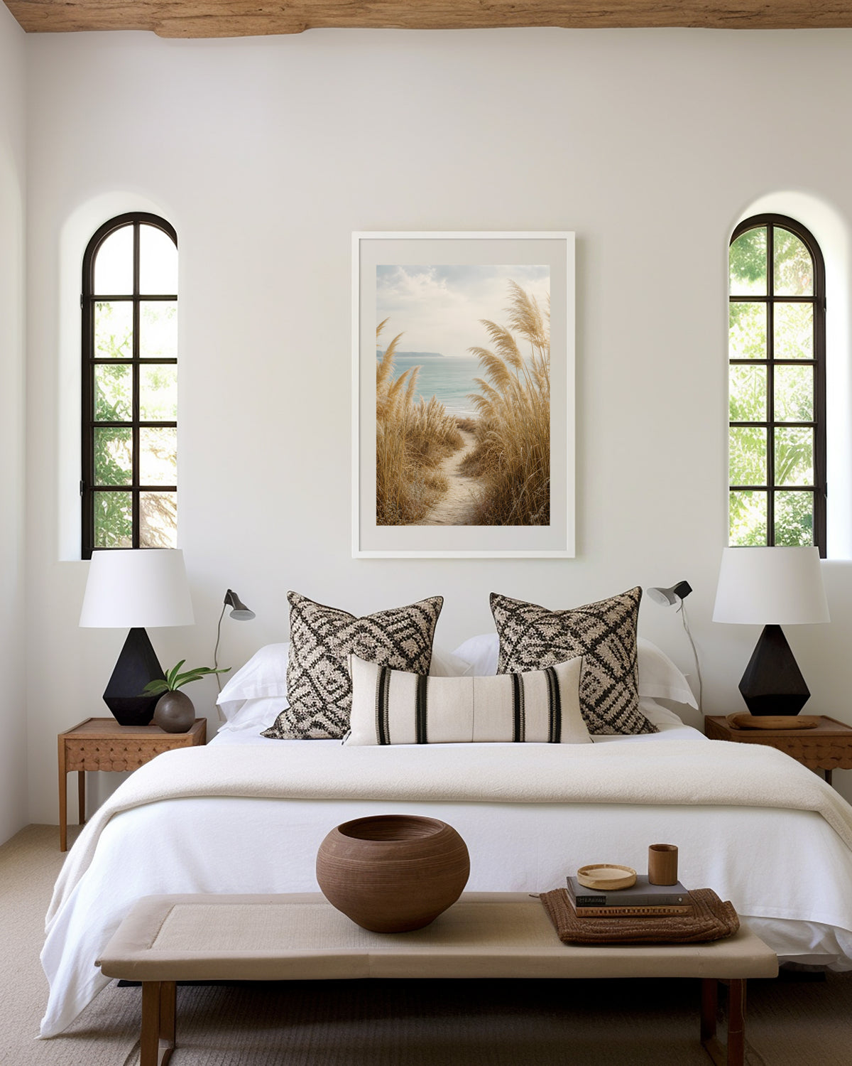 Motiv mit einem schmalen Sandpfad zwischen Pampasgräsern zum blauen Meer, als gerahmtes Poster in den Händen einer Frau.
