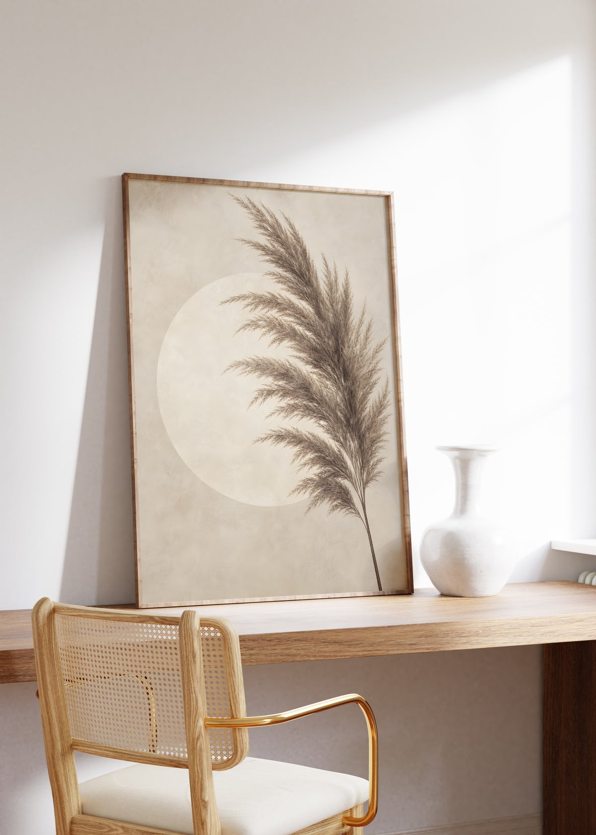 Gerahmtes Poster mit einem dunkelbraunen Pampaswedel vor einem hellen Kreis, auf einem Holztisch neben einer weißen Vase.