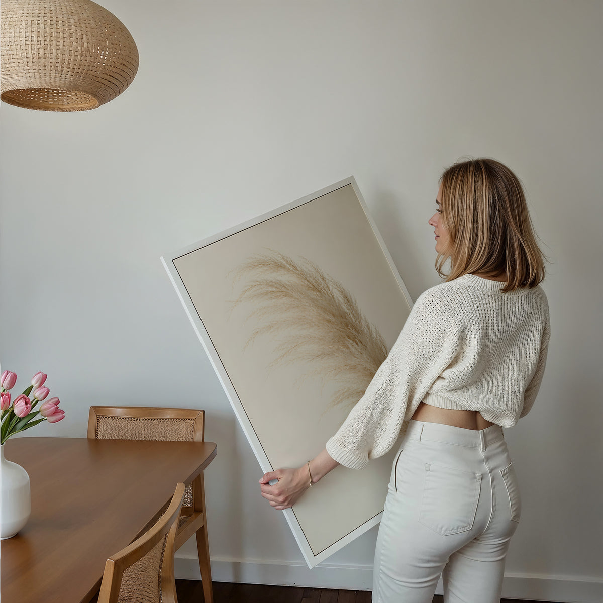 Motiv mit einem einzelnen flauschigen Pampaswedel in Cremebeige vor hellem Hintergrund, über einem Bett im hellen Schlafzimmer.