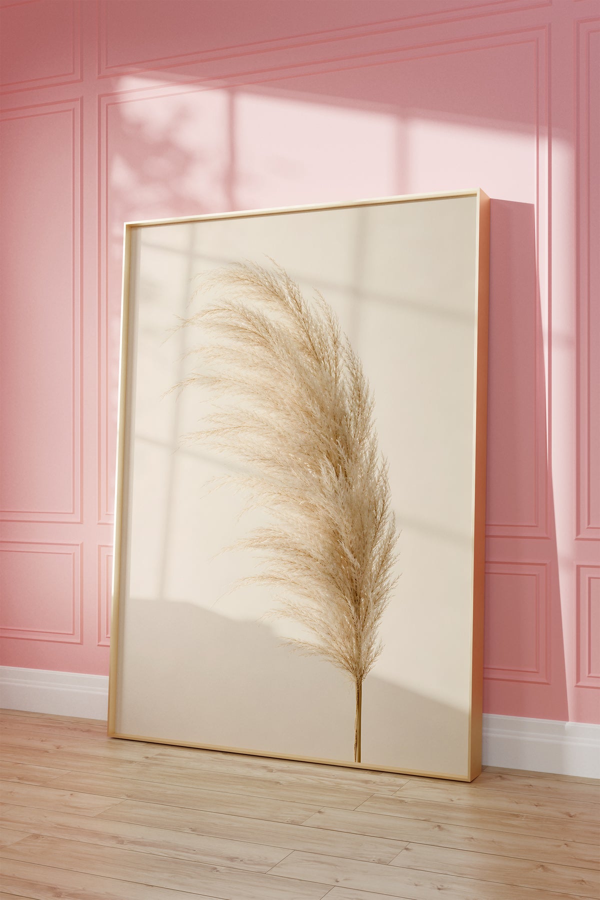Motiv mit einem einzelnen flauschigen Pampaswedel in Cremebeige vor hellem Hintergrund, als gerahmtes Poster vor einer rosafarbenen Wand.