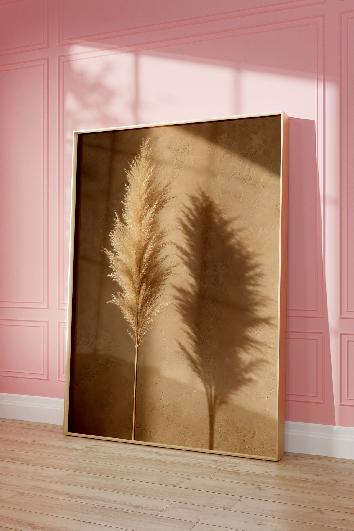 Motiv mit einem goldbeigen Pampaswedel und seinem Schatten auf einer warmbraunen Wand, als gerahmtes Poster vor einer rosafarbenen Wand.