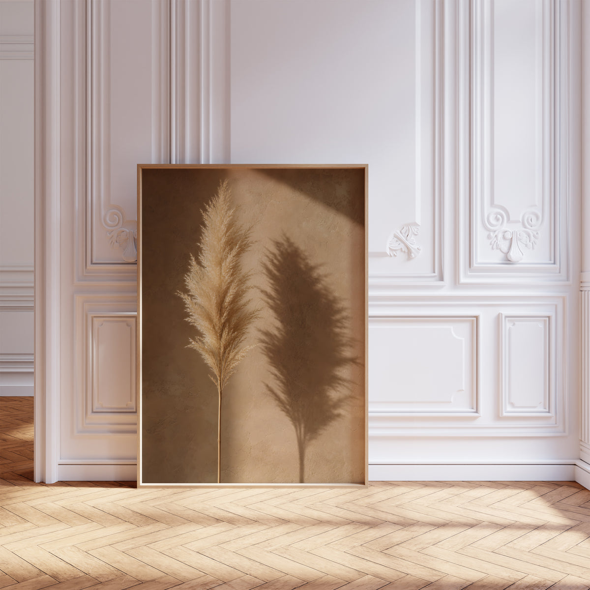 Gerahmtes Poster mit einem goldbeigen Pampaswedel und seinem Schatten auf einer warmbraunen Wand, vor einer weißen Wand mit Zierleisten.