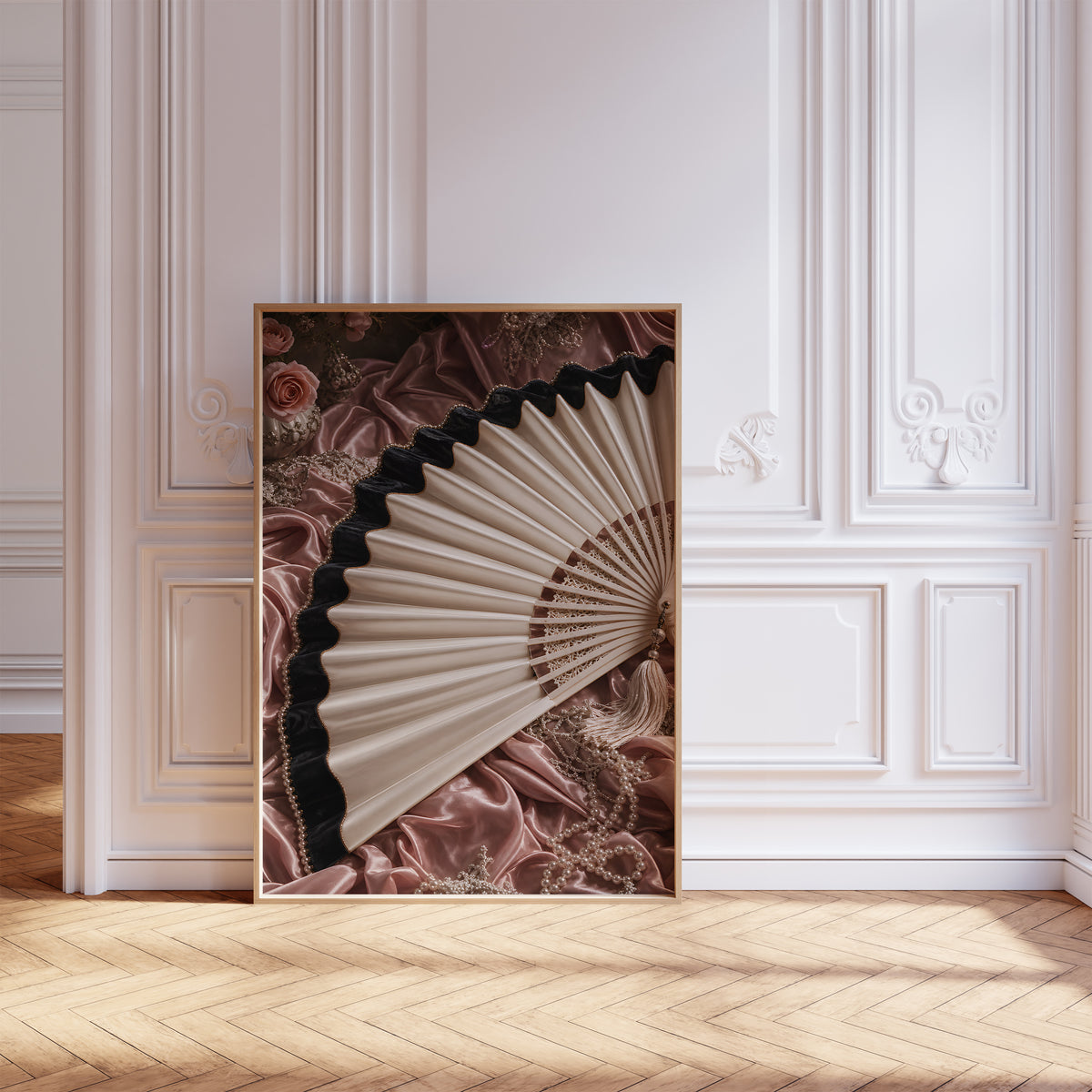 Gerahmtes Poster mit einem cremefarbenen Fächer mit schwarzem Saum auf roséfarbenem Satin, vor einer weißen Wand mit Zierleisten.