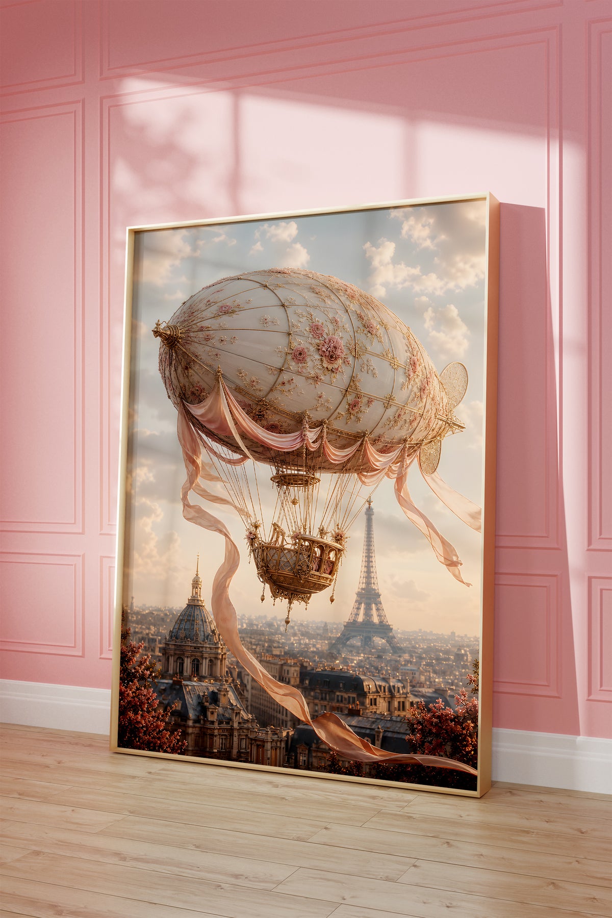 Motiv mit einem cremefarbenen Luftschiff mit Rosenmuster und Satinbändern über Paris, als gerahmtes Poster vor einer rosafarbenen Wand.