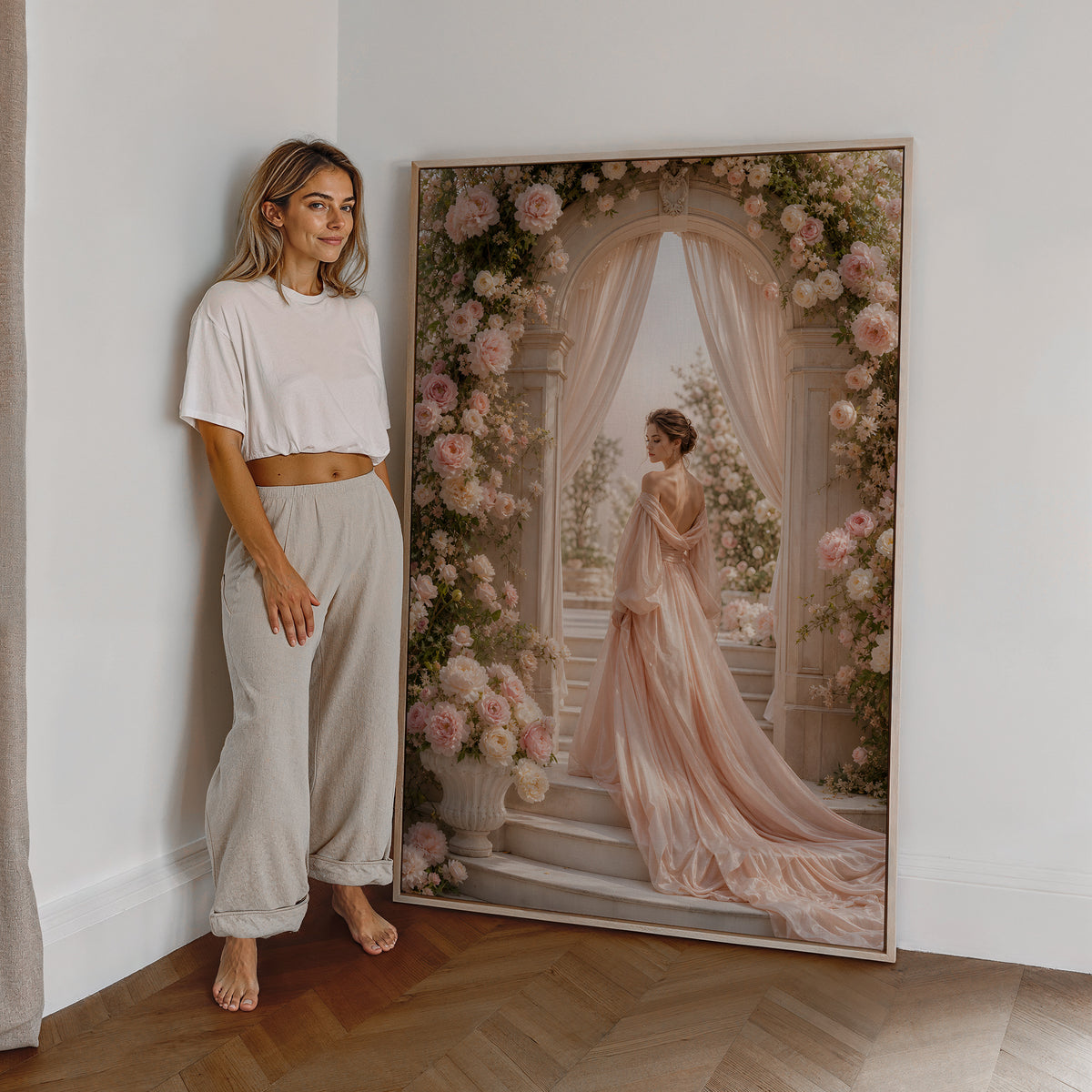 Motiv mit einer Frau im roséfarbenen Abendkleid unter einem üppigen Blütenbogen, als großes gerahmtes Wandbild neben einer Frau.