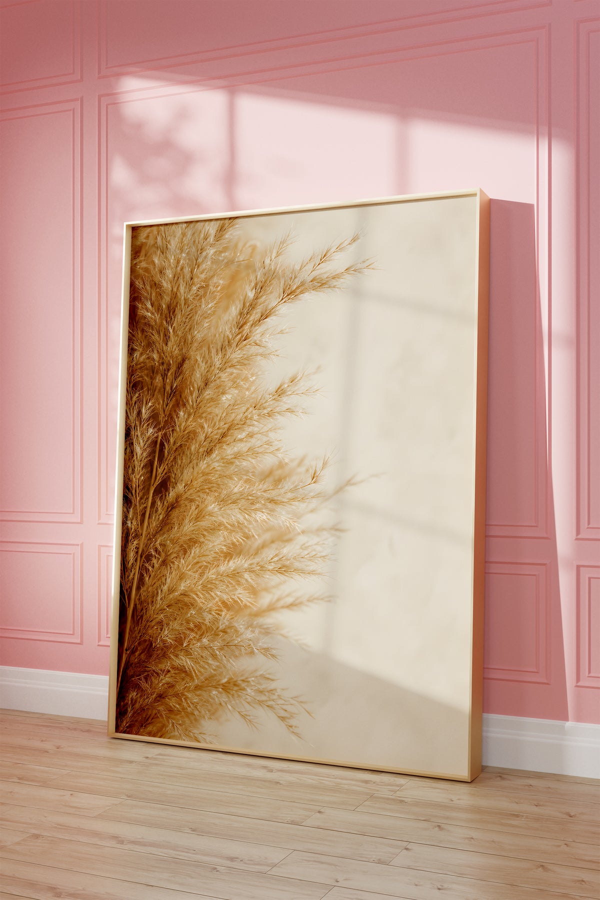 Motiv mit goldbeigen Pampasfasern am linken Rand vor hellem Hintergrund, als gerahmtes Poster vor einer rosafarbenen Wand.