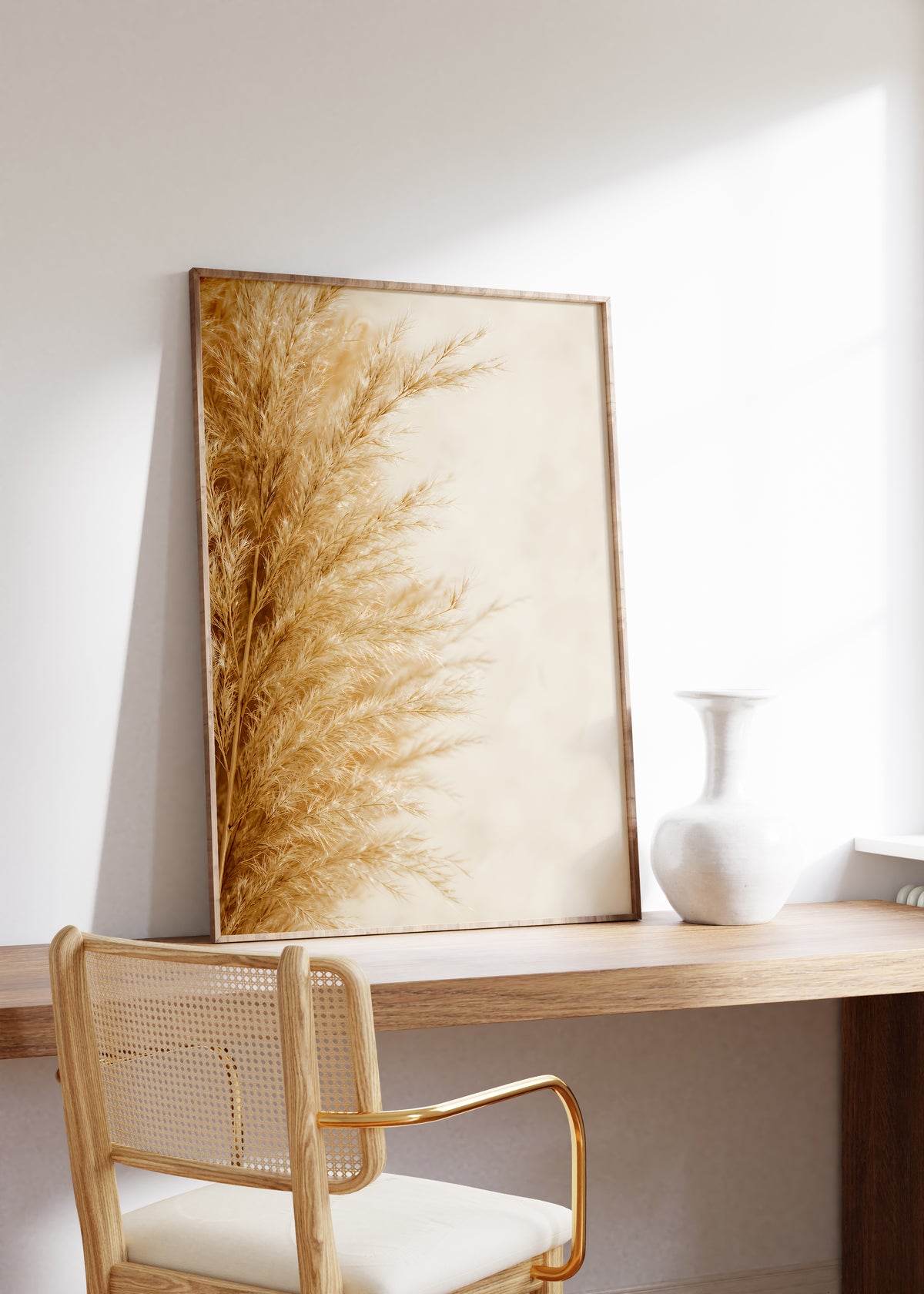 Gerahmtes Poster mit goldbeigen Pampasfasern am linken Rand vor hellem Hintergrund, auf einem Holztisch neben einer weißen Vase.