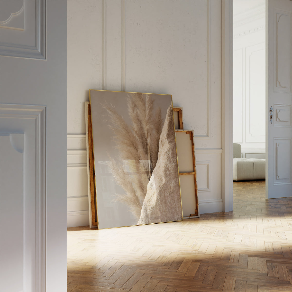 Motiv mit goldbraunen Pampaswedeln neben einer rauen sandfarbenen Steinfläche, als an die Wand gelehntes Poster neben leeren Rahmen.