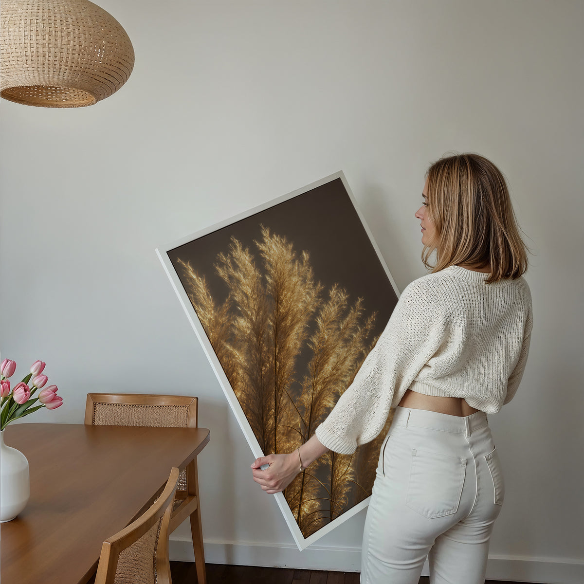 Motiv mit golden beleuchteten feinen Pampasfasern vor dunklem Hintergrund, über einem Bett im hellen Schlafzimmer.