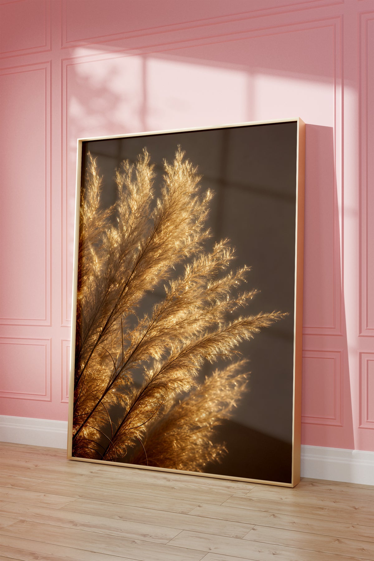 Motiv mit golden beleuchteten feinen Pampasfasern vor dunklem Hintergrund, als gerahmtes Poster vor einer rosafarbenen Wand.