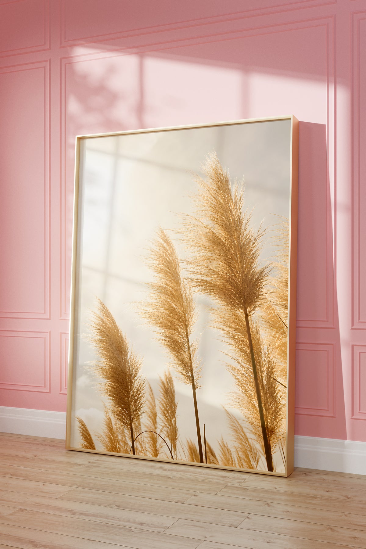 Motiv mit goldenen Pampasgräsern im hellen Gegenlicht, als gerahmtes Poster vor einer rosafarbenen Wand.