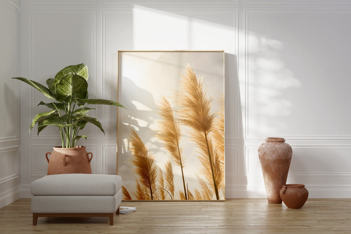 Motiv mit goldenen Pampasgräsern im hellen Gegenlicht, als gerahmtes Poster neben Sessel und Zimmerpflanze.