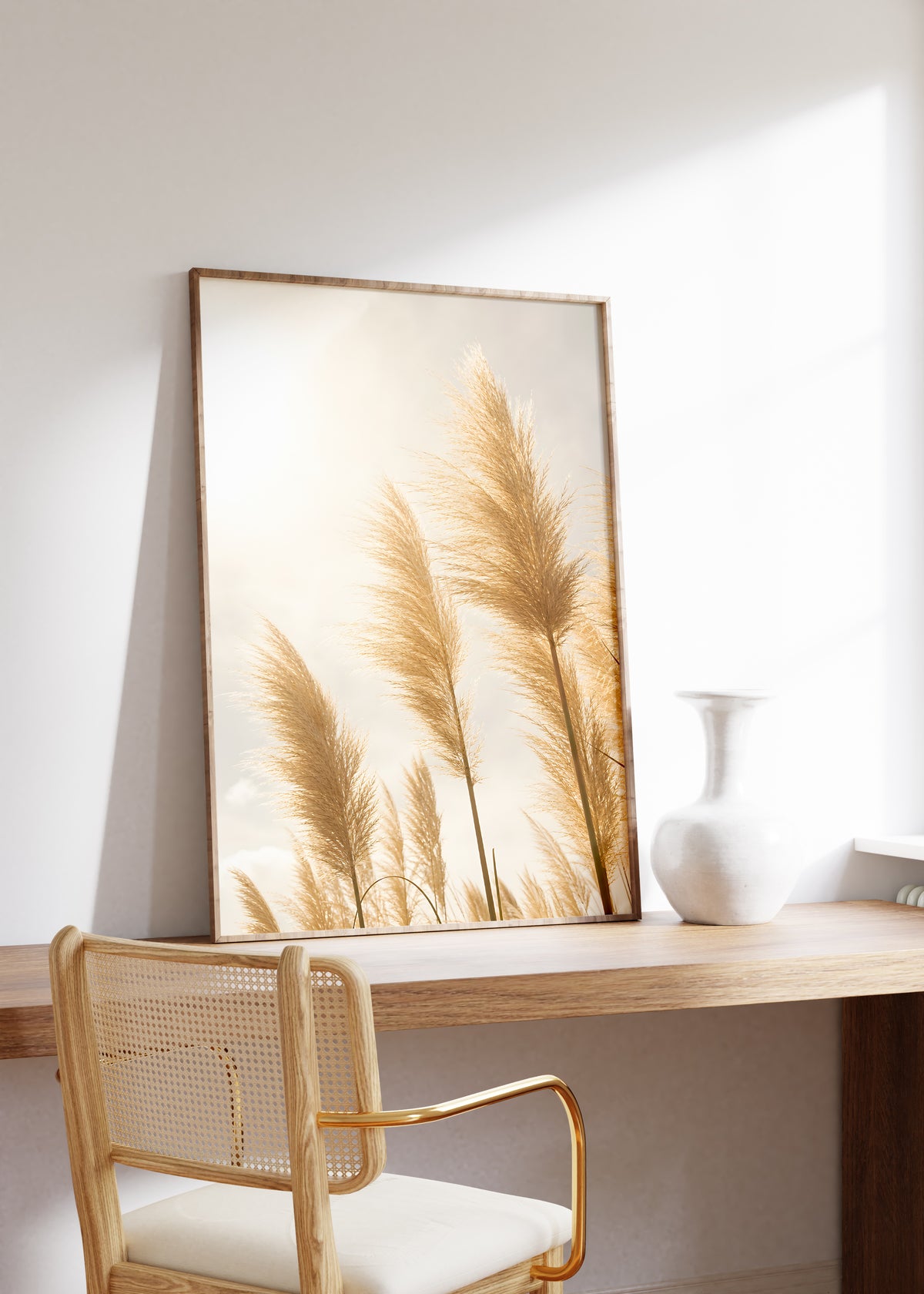 Gerahmtes Poster mit goldenen Pampasgräsern im hellen Gegenlicht, auf einem Holztisch neben einer weißen Vase.