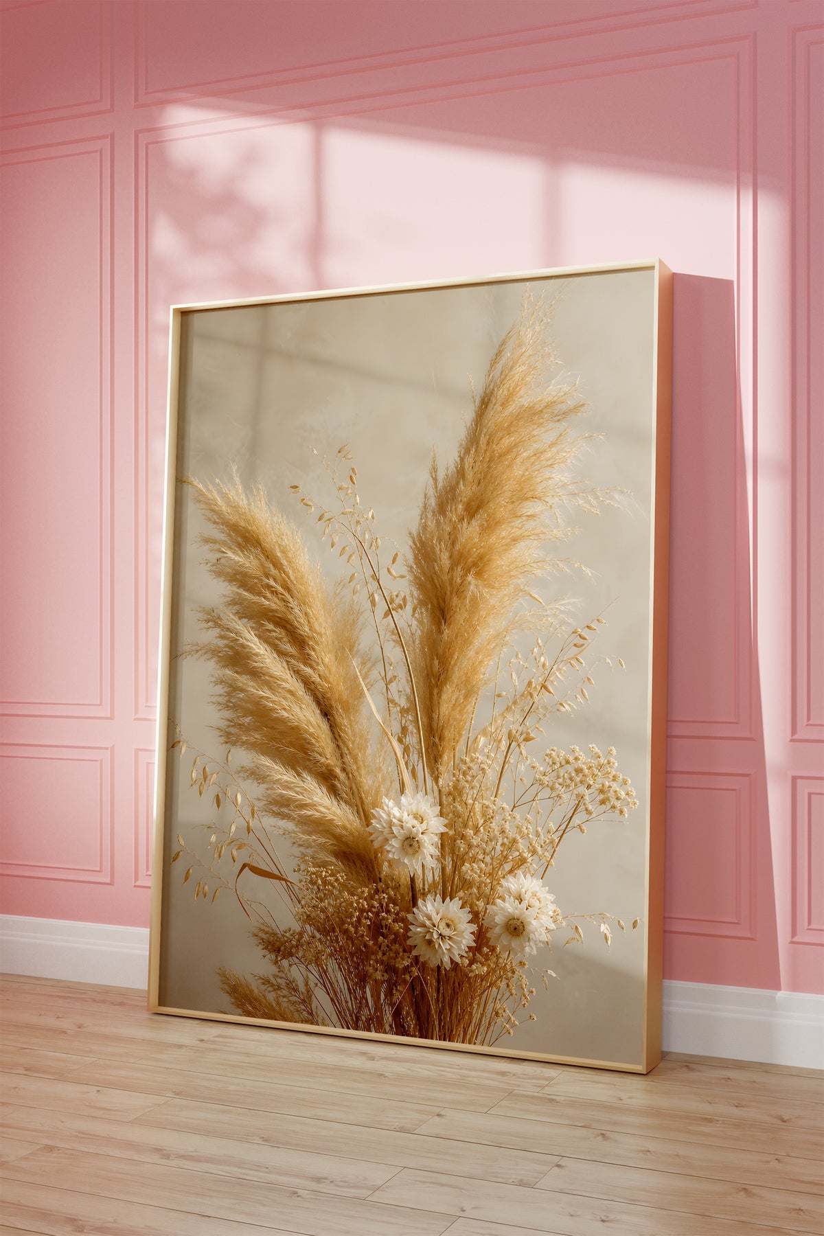 Motiv mit einem goldenen Strauß aus Pampasgras und kleinen hellen Trockenblumen, als gerahmtes Poster vor einer rosafarbenen Wand.