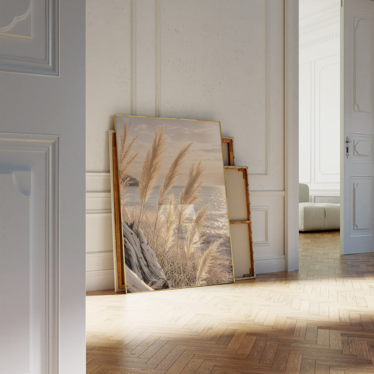 Motiv mit goldenen Pampasgräsern vor glitzerndem Meer im Abendlicht, als an die Wand gelehntes Poster neben leeren Rahmen.