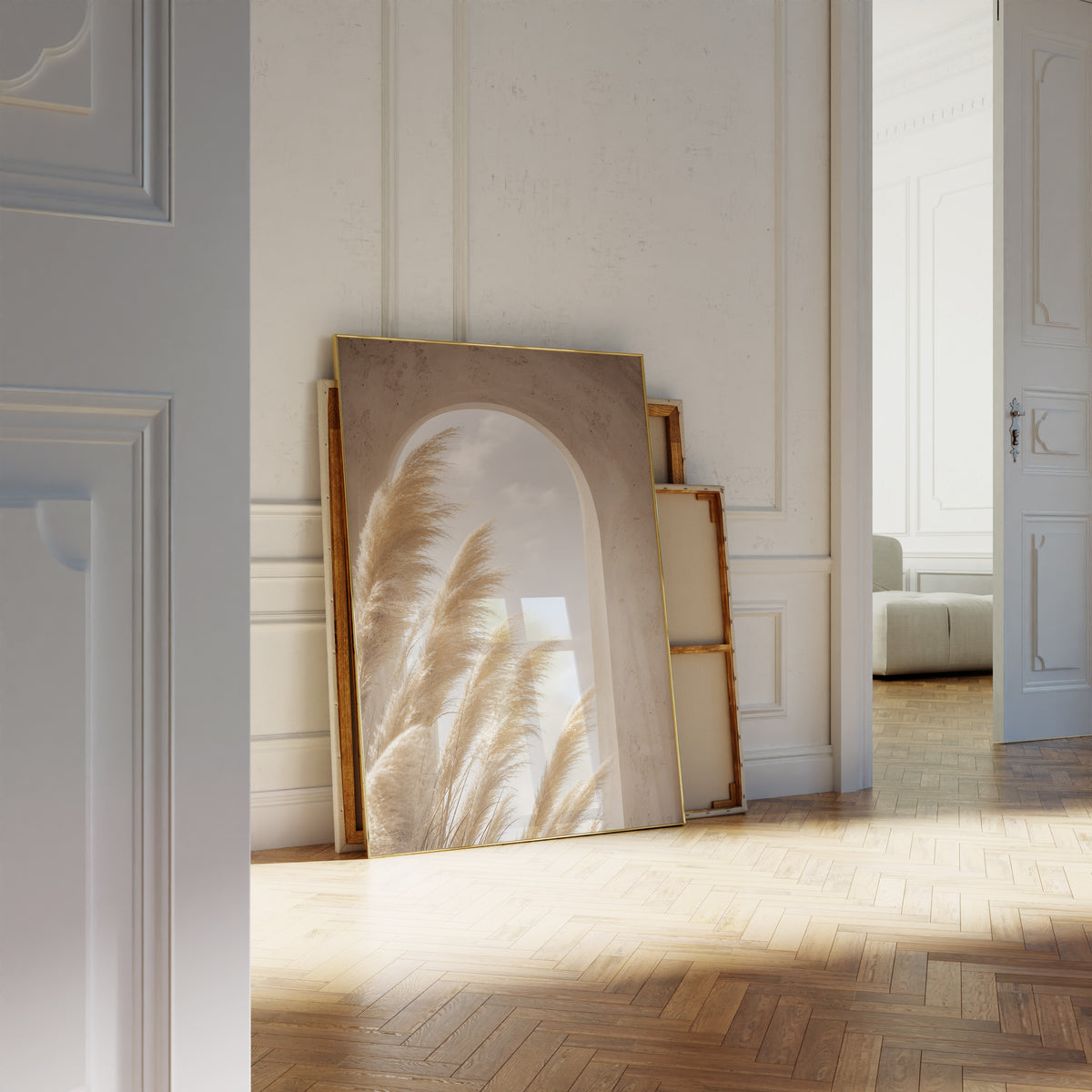 Motiv mit goldenen Pampaswedeln vor einem sandfarbenen Rundbogen mit Blick zum Himmel, als an die Wand gelehntes Poster neben leeren Rahmen.