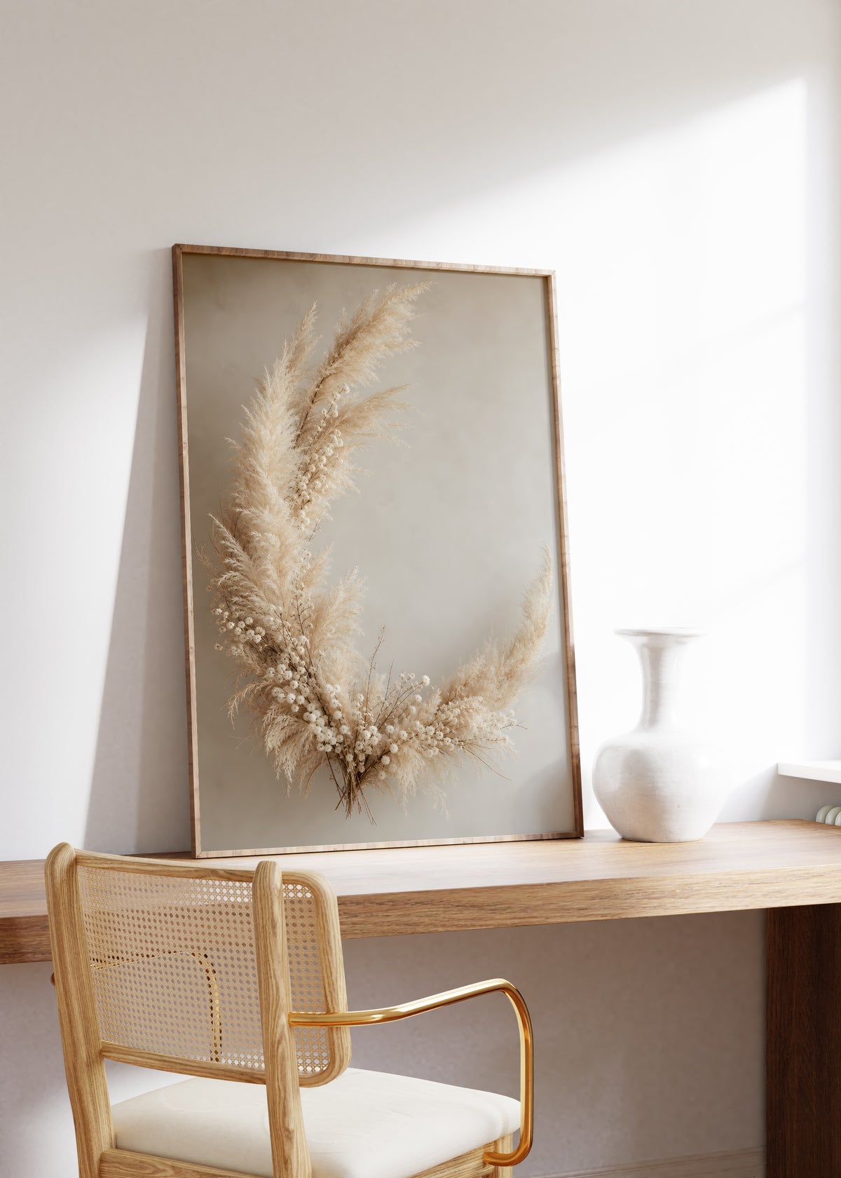 Gerahmtes Poster mit einem halbmondförmigen Arrangement aus Pampasgras und kleinen hellen Trockenblumen, auf einem Holztisch neben einer weißen Vase.