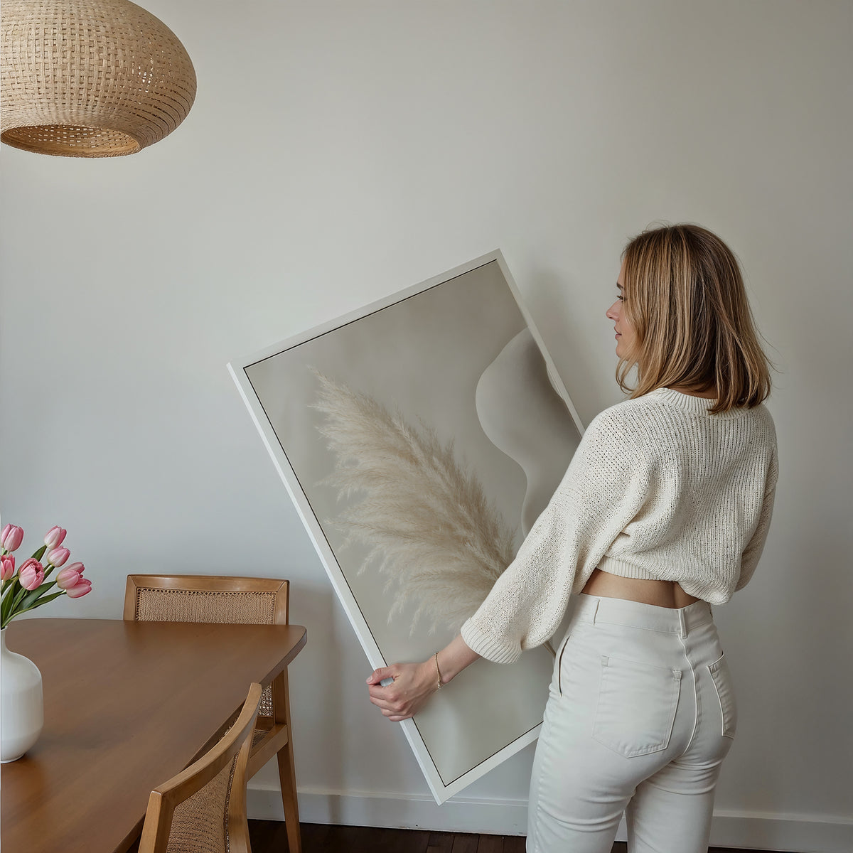 Motiv mit einem hellen Pampaswedel neben einer geschwungenen weißen Skulptur, über einem Bett im hellen Schlafzimmer.