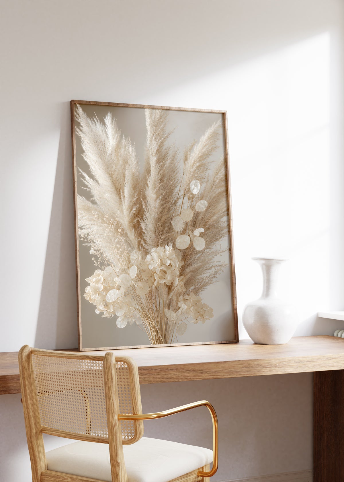 Gerahmtes Poster mit einem cremeweißen Bouquet aus Pampasgras, Silberblatt und hellen Blüten, auf einem Holztisch neben einer weißen Vase.