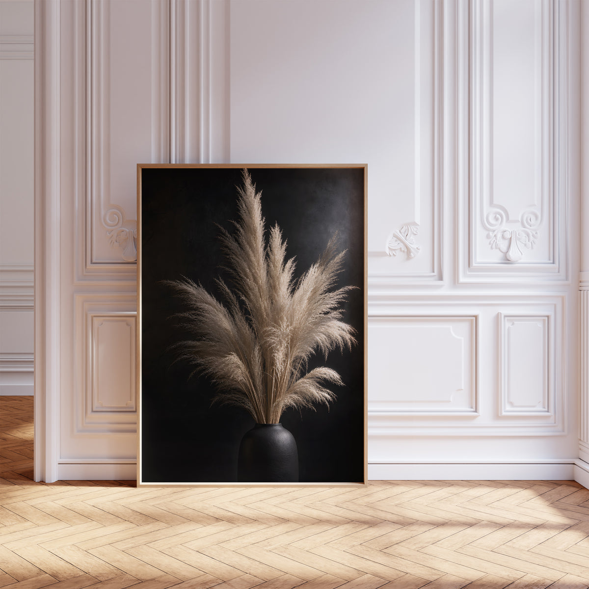 Gerahmtes Poster mit einem hellen Pampasbouquet in einer schwarzen Vase vor schwarzem Hintergrund, vor einer weißen Wand mit Zierleisten.