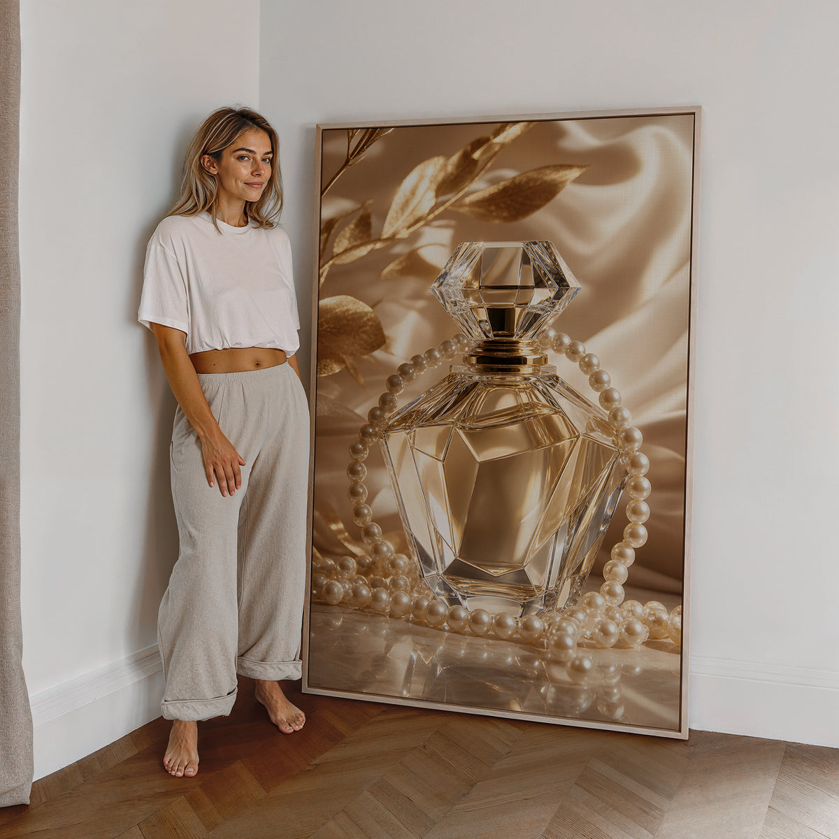 Motiv mit einem goldfarbenen Kristall-Parfumflakon mit Perlenkette auf Satin, als großes gerahmtes Wandbild neben einer Frau.