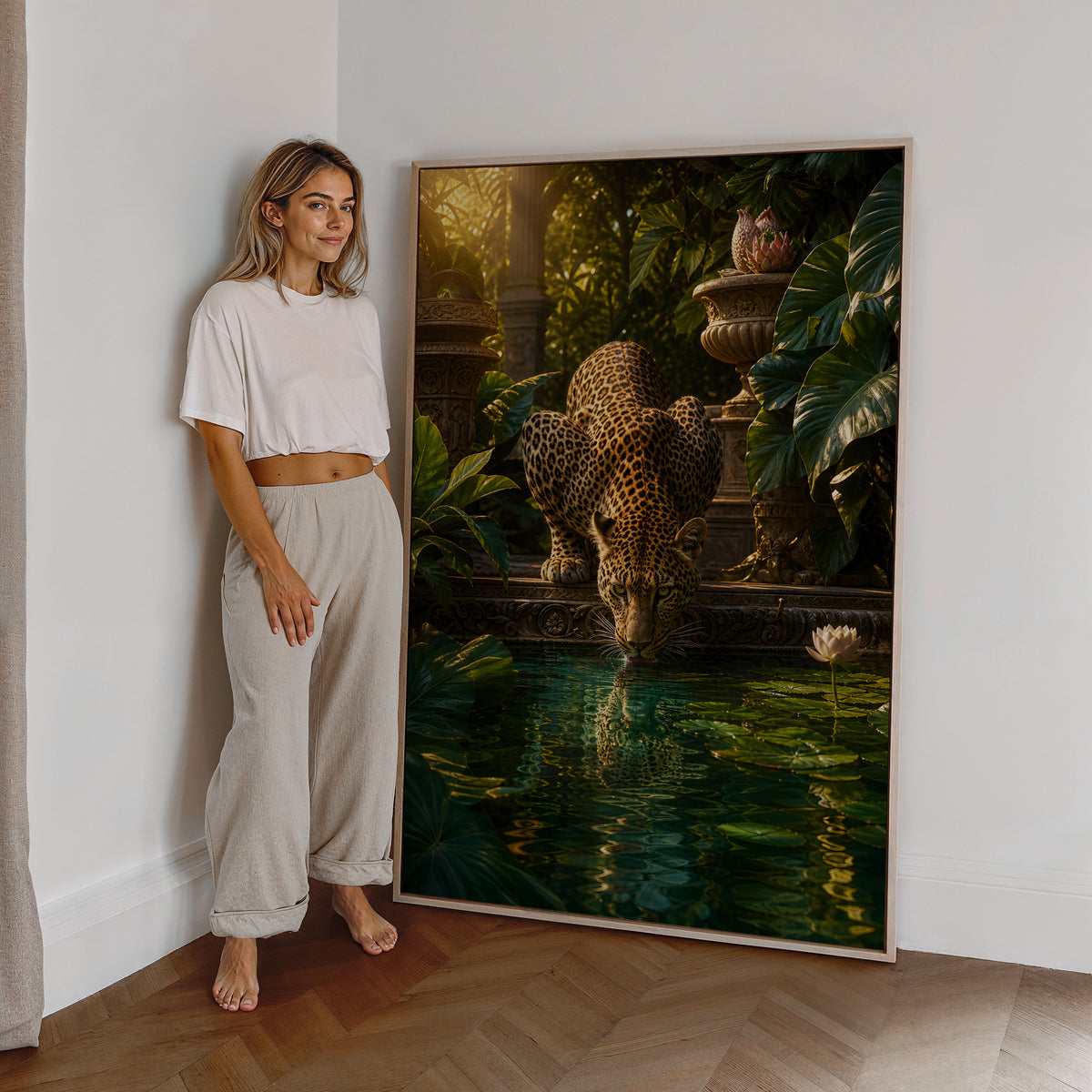 Motiv mit einem trinkenden Leoparden an einem Teich mit tropischen Pflanzen, als großes gerahmtes Wandbild neben einer Frau.