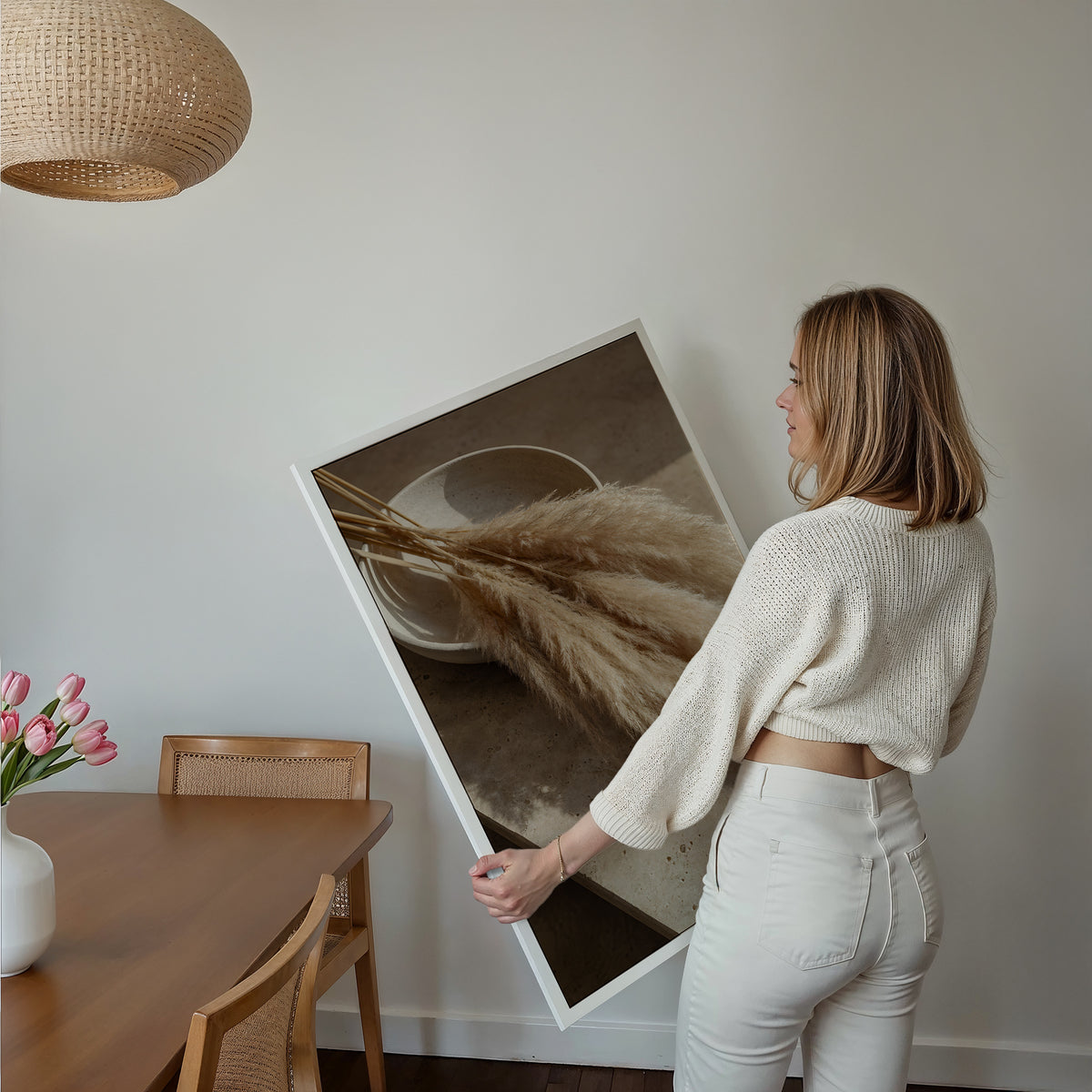 Motiv mit einem liegenden Pampasbouquet auf einer Steinfläche neben einer Keramikschale, über einem Bett im hellen Schlafzimmer.